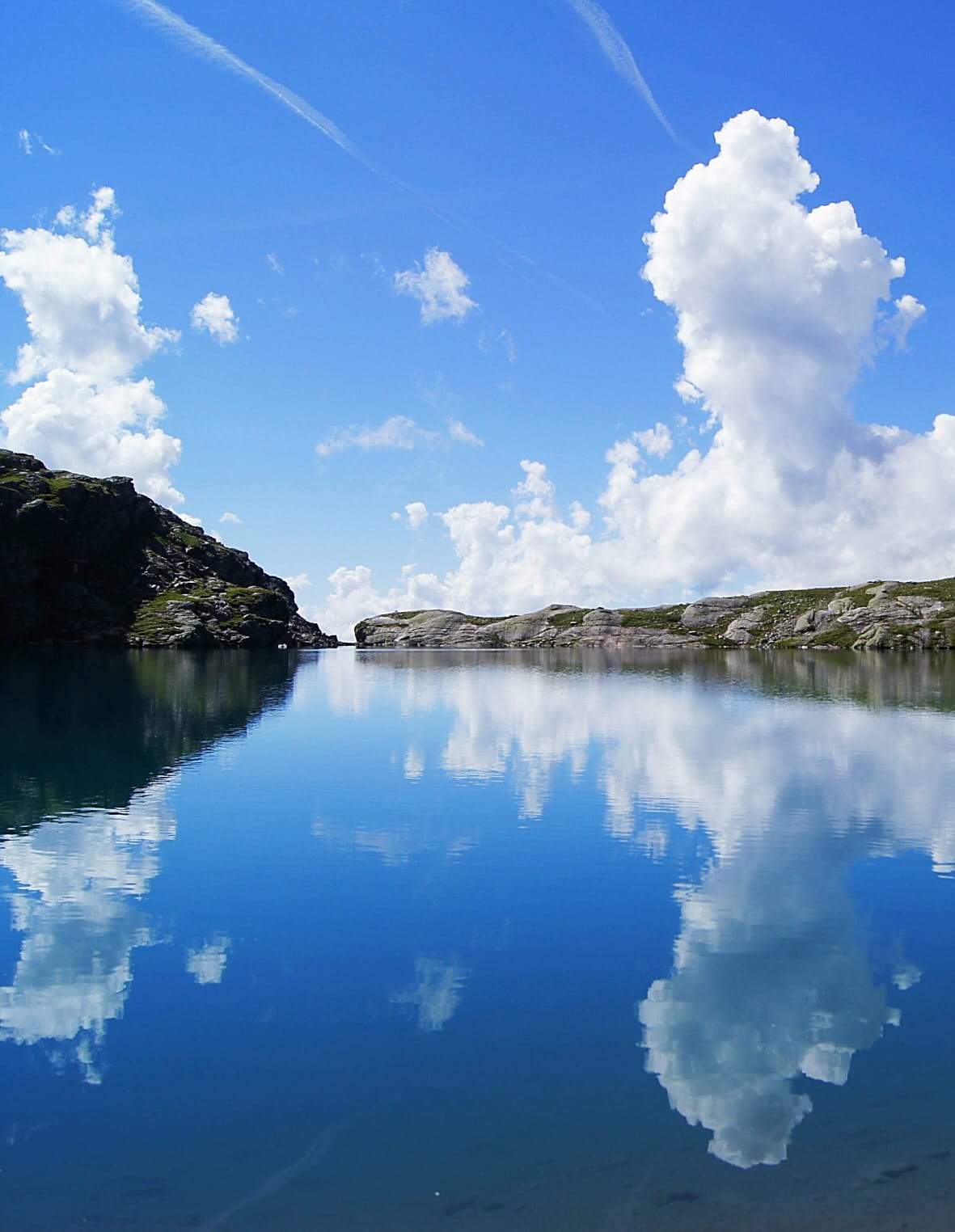 Bergsee mit Wolkenspiegelung in den Bergen